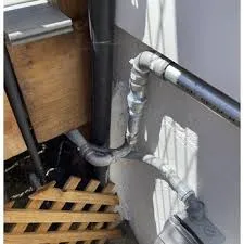 An outdoor plumbing setup with pipes connected carefully against a wall, showcasing the workmanship of Mason Plumbing, Inc. in San Anselmo.
